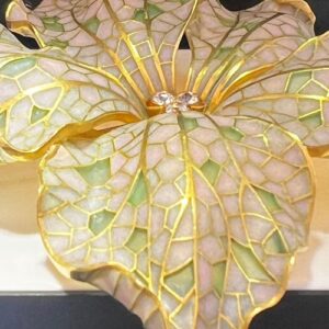 . I utställningen ”The Atelier” visades olika klassiska hantverk inom smycketillverkning. Här en brosch med plique-à-jour. Det betyder ungefär ”släppa in dagsljus” på franska, och är en emaljeringsteknik där transparent emalj appliceras i celler utan bakgrundsplatta vilket skapar en effekt av miniatyrmålade glasfönster där ljuset lyser igenom.